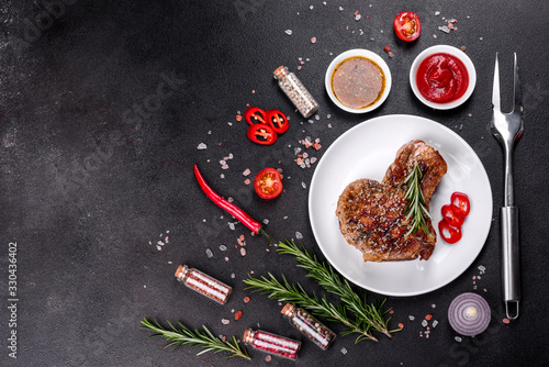 Fototapeta Naklejka Na Ścianę i Meble -  Fresh delicious juicy steak on the bones with vegetables and spices against a dark background