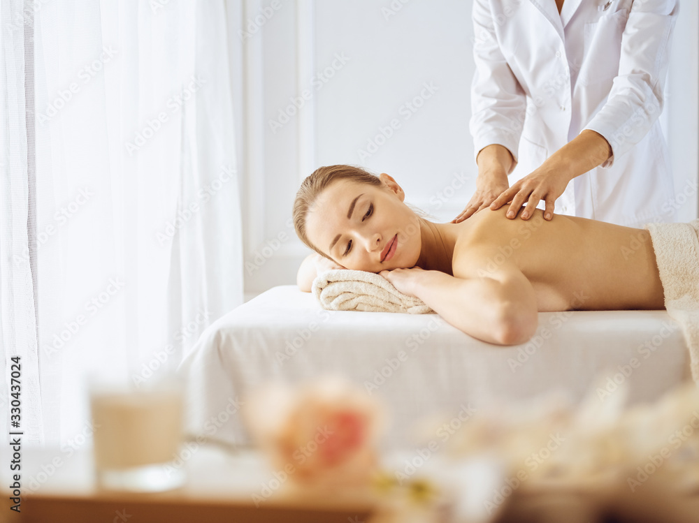 Obraz premium Beautiful woman enjoying back massage with closed eyes. Spa treatment concept