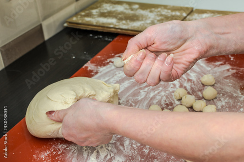 Woman cook sculpts round balls of dough from flour