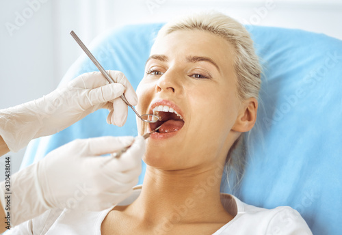 Smiling blonde woman examined by dentist at dental clinic. Healthy teeth and medicine concept