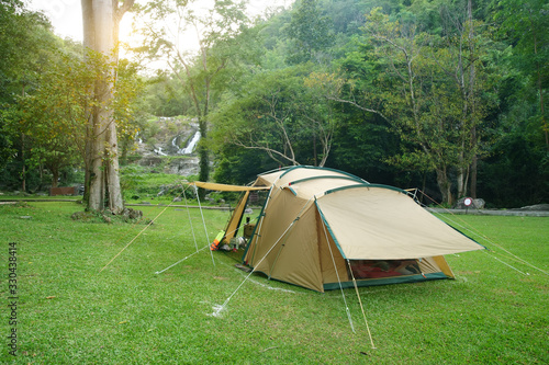 camping tent on waterfall with tree in green jungle or forest for summer winter holiday relax and vacation travel trip with trekking and picnic on meadow grass and sunlight at Khlong Nam Lai Waterfall