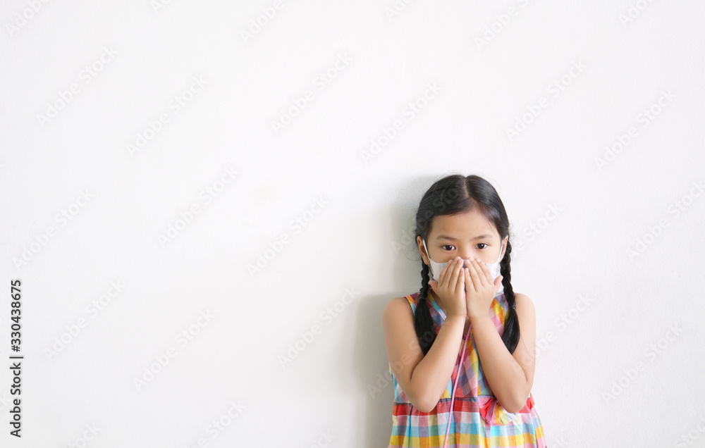 Asian child or kid girl wear N95 paper face mask and sick on nose with cold cough and protect PM2.5 dust or influenza virus and bacteria from smoke with hand close mouth on street and white background Asian child or kid girl wear N95 paper face mask and sick on nose with cold cough and protect PM2.5 dust or influenza virus and bacteria from smoke with hand close mouth on street and white background
