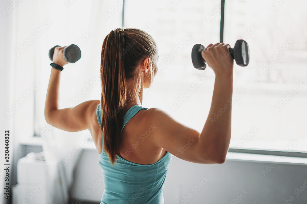 Attractive fit young woman in sport wear fitness model girl trains with dumbbells studio workout classes Attractive fit young woman in sport wear fitness model girl trains with dumbbells studio workout classes