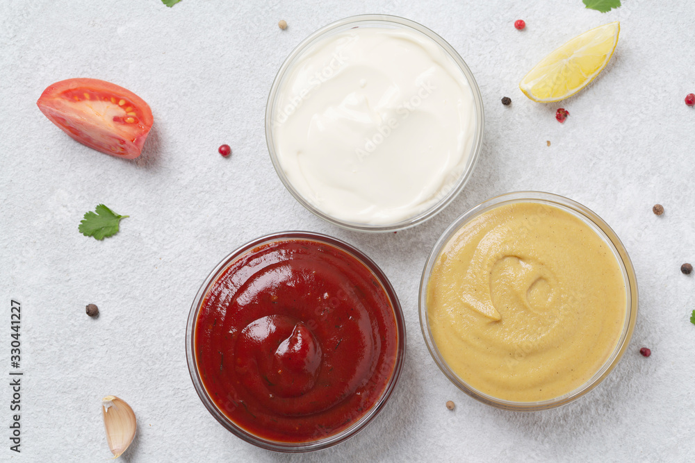 Assortment of sauces: ketchup, mayonnaise and mustard. Different delicious sauces on grey table. Selective focus Assortment of sauces: ketchup, mayonnaise and mustard. Different delicious sauces on grey table. Selective focus