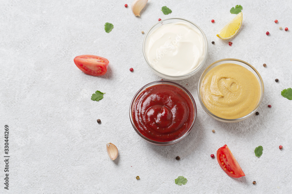 Assortment of sauces: ketchup, mayonnaise and mustard. Different delicious sauces on grey table. Selective focus Assortment of sauces: ketchup, mayonnaise and mustard. Different delicious sauces on grey table. Selective focus
