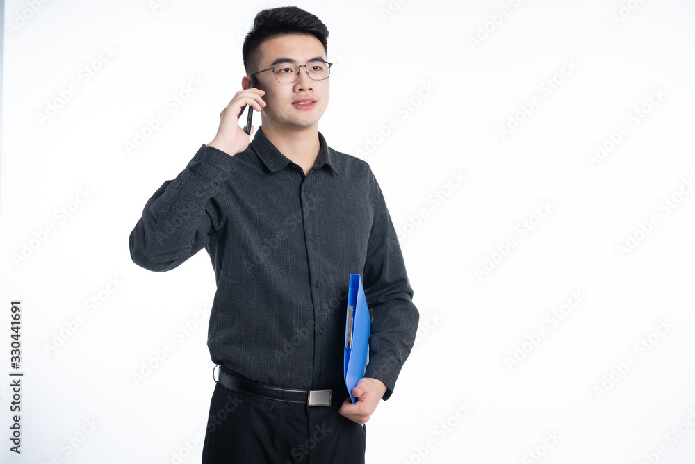 A young Asian business man stood behind his desk A young Asian business man stood behind his desk
