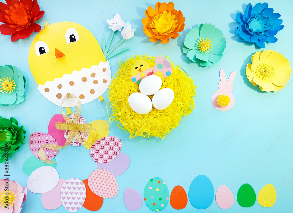 Child made crafts his own hands at Easter. Handmade nest with eggs, flowers, chicken, chicken in an egg, frame of eggs. Cute art creativity on blue background. Flat lay, top view, close up, copy space Child made crafts his own hands at Easter. Handmade nest with eggs, flowers, chicken, chicken in an egg, frame of eggs. Cute art creativity on blue background. Flat lay, top view, close up, copy space