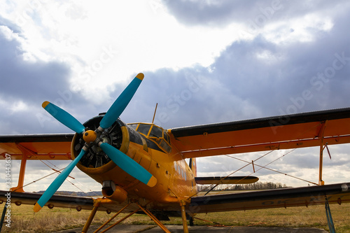 Yellow biplane from front standing on airports with cloud sky