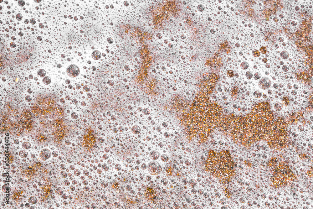 Large bubbles from white foam of a wave on a sandy beach. sand beach background, beautiful beach surface texture. copy space. Large bubbles from white foam of a wave on a sandy beach. sand beach background, beautiful beach surface texture. copy space.