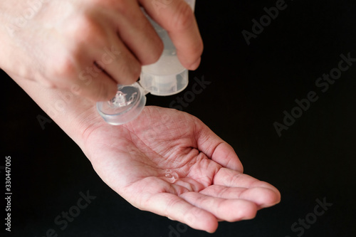 Selective focus of Asian men hand using Alcohol gel  hand sanitizer for personal hygiene on black background to protect  prevent from virus and illness during Corona virus outbreak or Covid 2019.