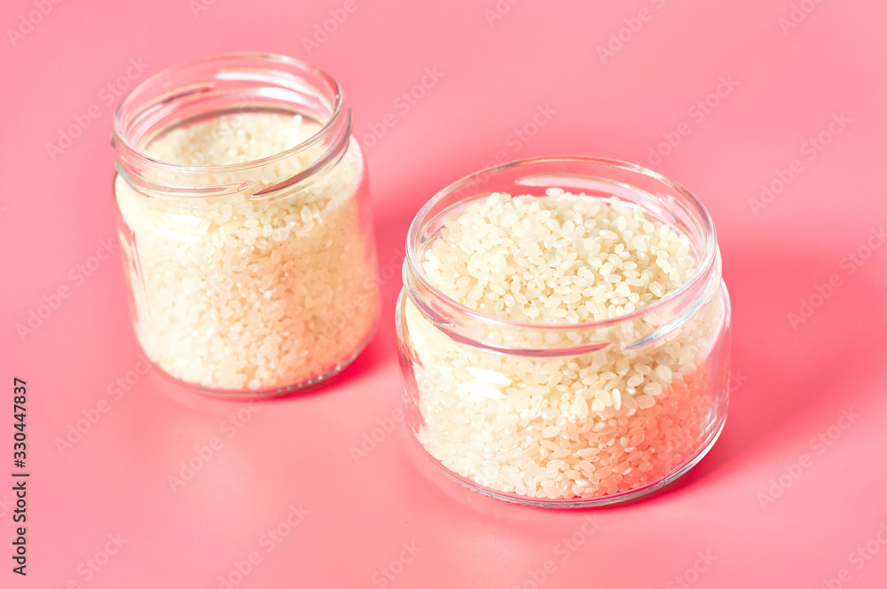Two jars of grain of rice on pink background Two jars of grain of rice on pink background