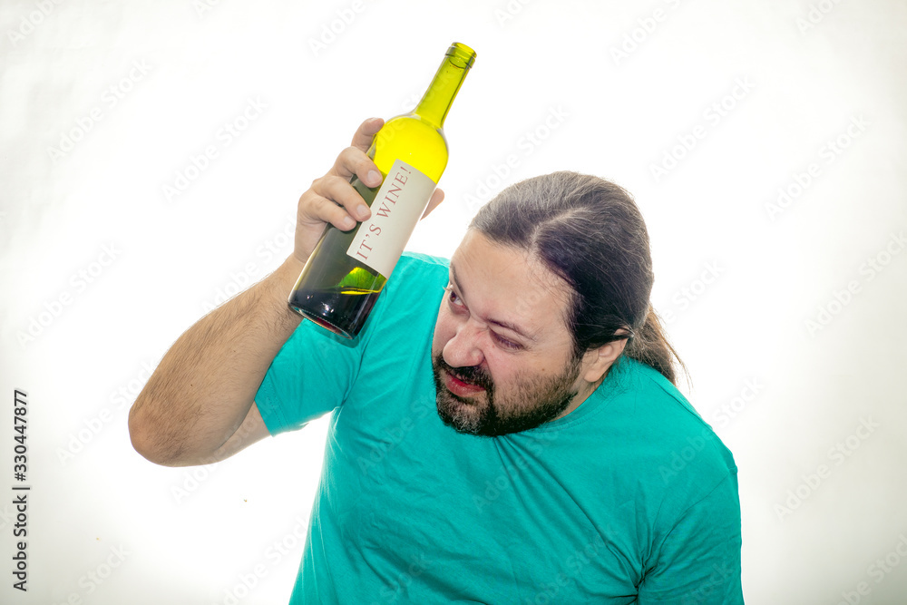 An unshaven young man holds a bottle of wine with both hands and does not stare intently. An unshaven young man holds a bottle of wine with both hands and does not stare intently.
