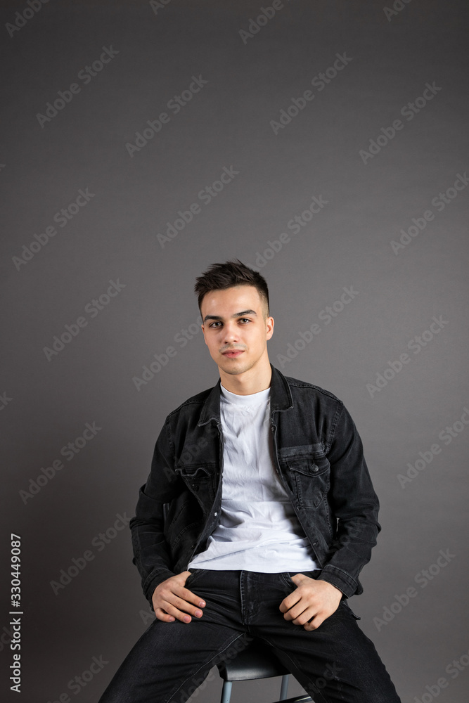 Fototapeta premium Young serious man posing in studio. Gray background