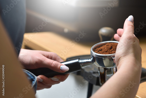 Barista makes coffee and holds portafilter in his hands from a coffee machine. Close-up