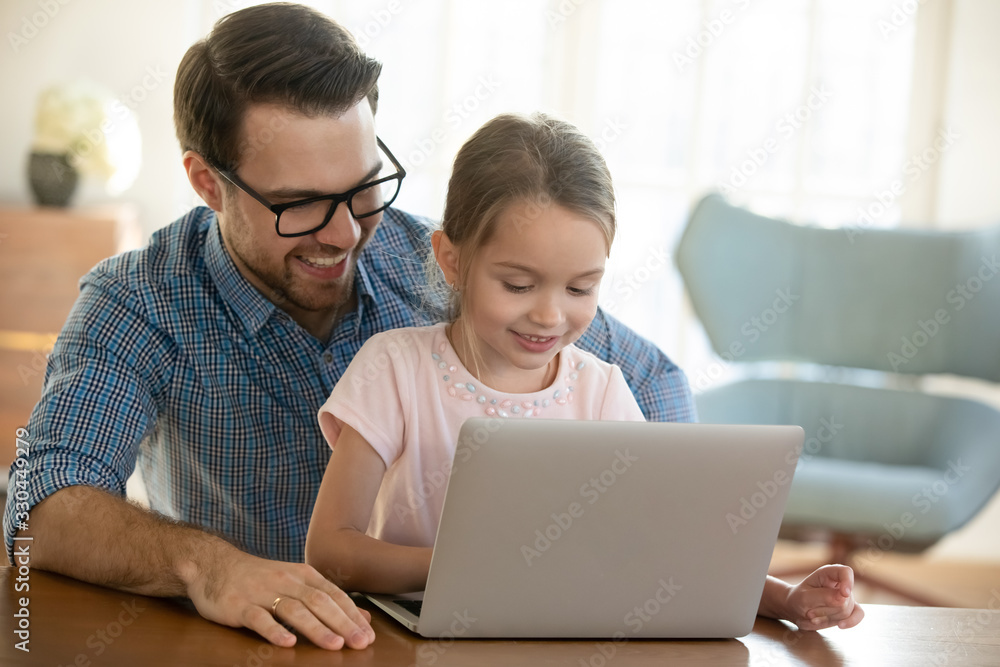 Head shot smiling young father in eyeglasses cuddling small preschool daughter, watching funny video on computer. Happy single dad shopping online on laptop with adorable little child girl at home. Head shot smiling young father in eyeglasses cuddling small preschool daughter, watching funny video on computer. Happy single dad shopping online on laptop with adorable little child girl at home.