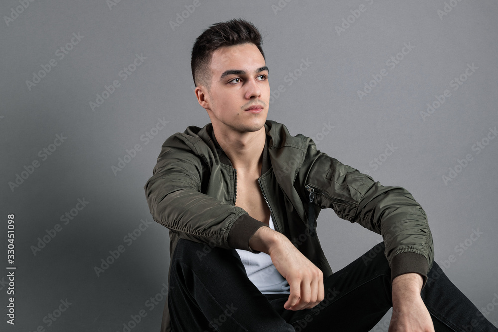 Fototapeta premium Young serious man posing in studio. Gray background