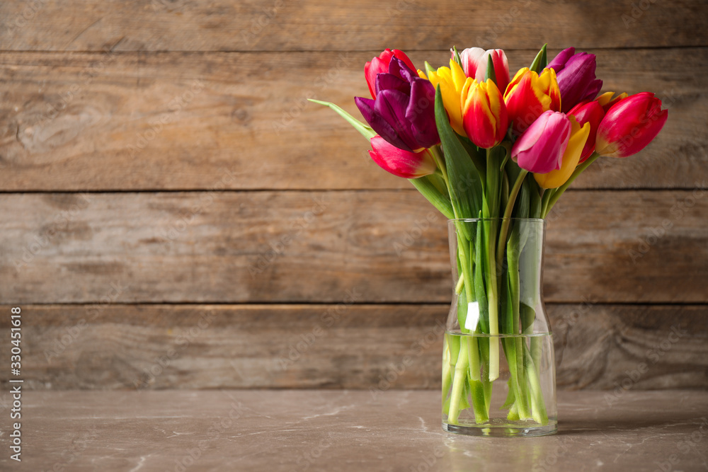 Beautiful spring tulips in vase on table against wooden background. Space for text Beautiful spring tulips in vase on table against wooden background. Space for text
