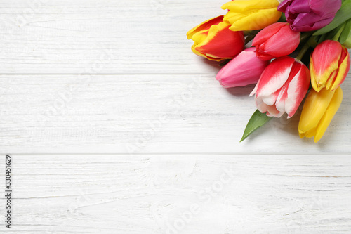 Fototapeta Naklejka Na Ścianę i Meble -  Beautiful spring tulips on white wooden table, flat lay. Space for text