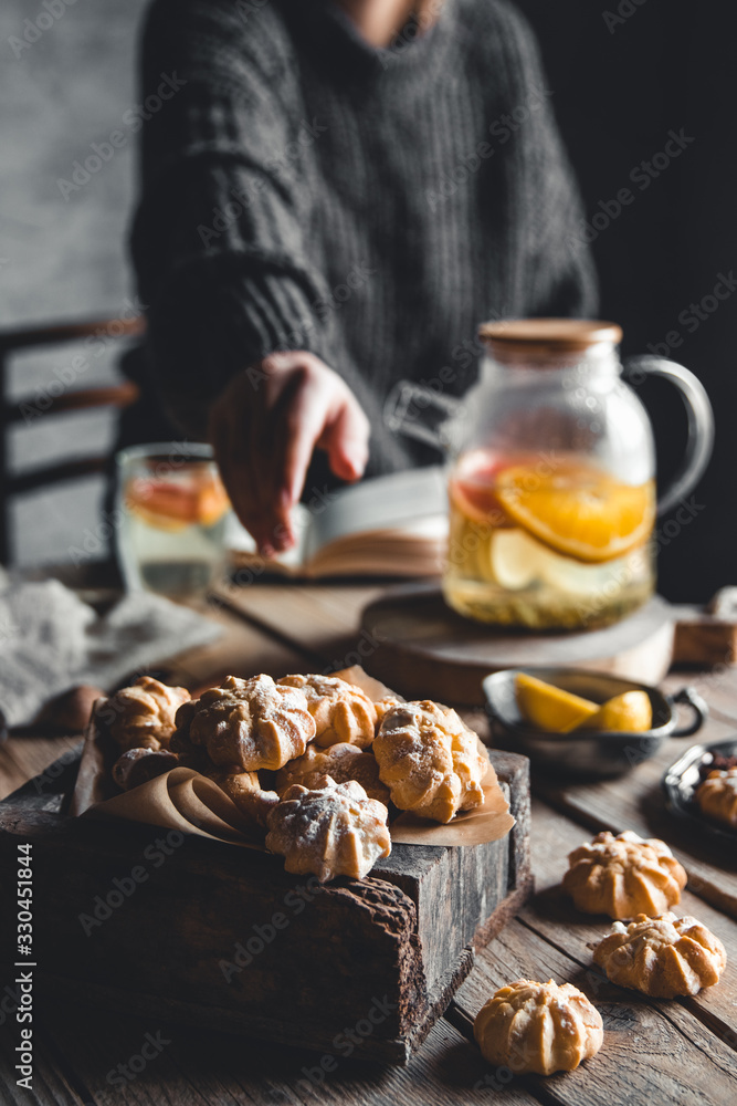 A woman reaches for a cake and drinks grapefruit tea. Healthy drink. A woman reaches for a cake and drinks grapefruit tea. Healthy drink.