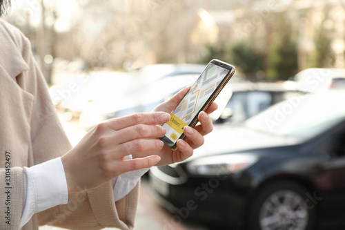 Woman ordering taxi with smartphone on city street, closeup photo