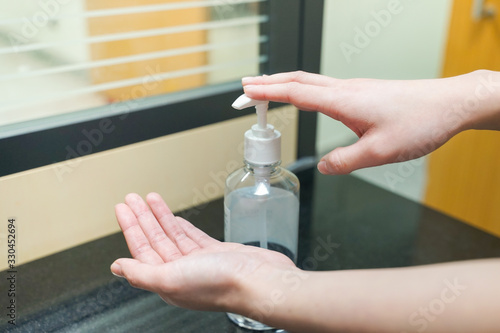 A woman using sanitizer alcohol hand rub for hands hygiene at home or public space  hospital clinic for protect covid 19 spread epidemic prevention.