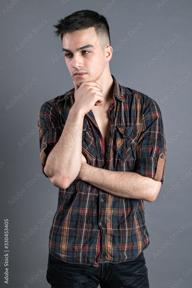 Young serious man posing in studio. Gray background