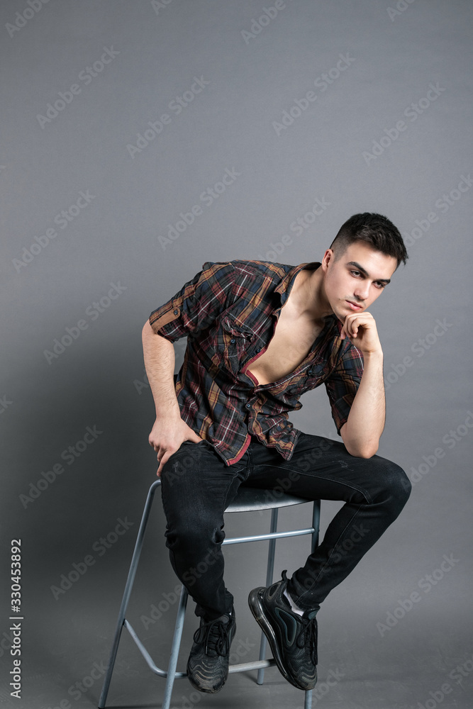 Young serious man posing in studio. Gray background Young serious man posing in studio. Gray background