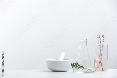 Ingredients for herbal cosmetic products and  laboratory glassware on white table. Space for text