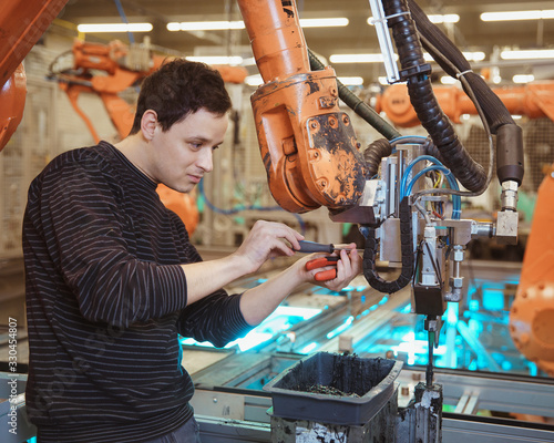 engineer performs maintenance of industrial robot in a factory