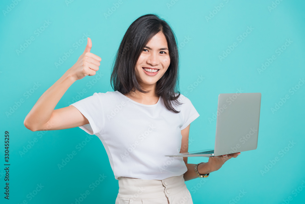 woman smile white teeth standing to hold laptop computer and showing thumb up woman smile white teeth standing to hold laptop computer and showing thumb up
