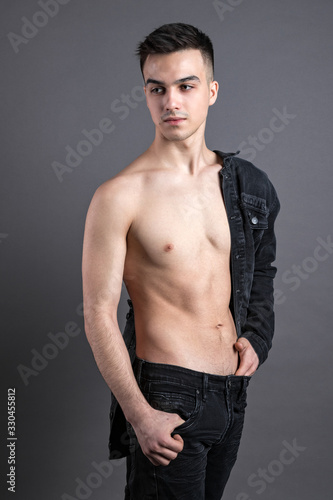 Sexy young man posing in studio. Gray background