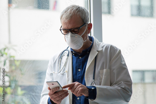 doctor with mask using mobile phone photo
