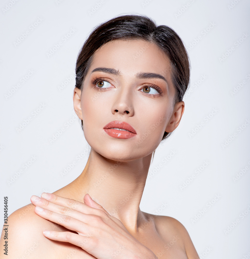 Portrait of beautiful  brunette girl which touching her fresh face. Beautiful face of young woman with health fresh skin.  Beautiful face of young adult woman with clean fresh skin. Skin care.