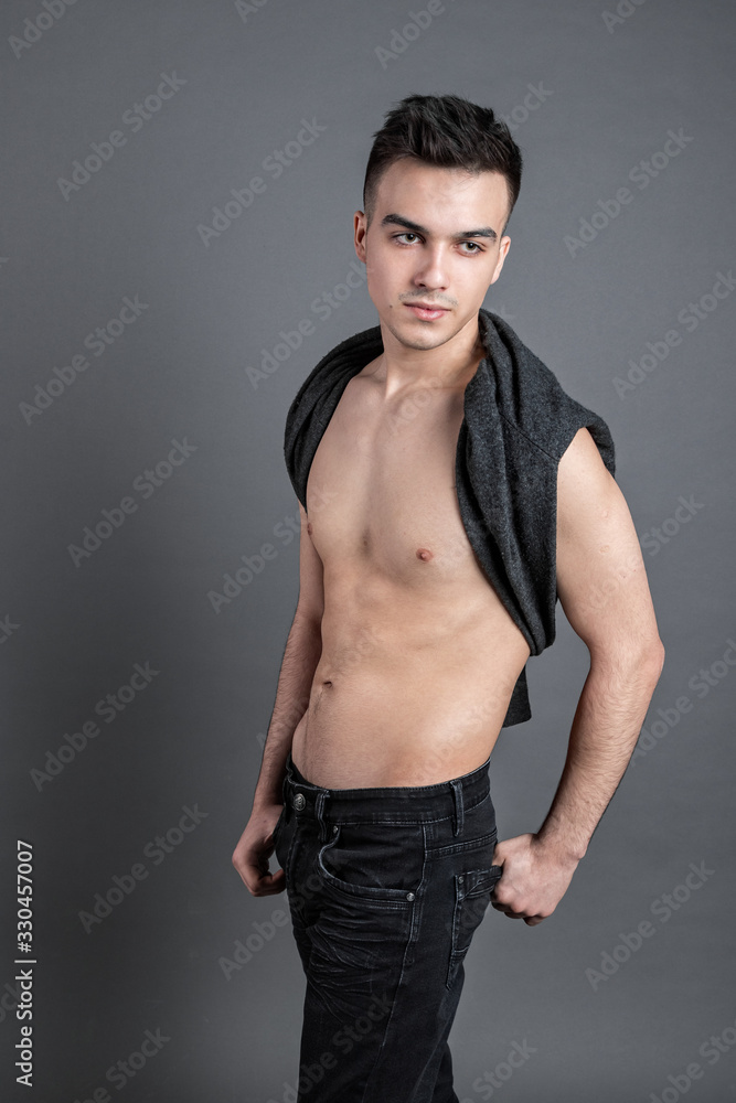 Sexy young man posing in studio. Gray background
