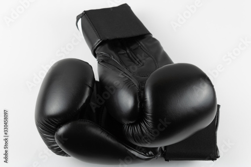 Close-up of black boxing gloves on white background. © Francisco