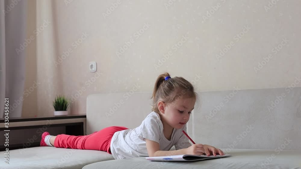 Four years little girl with pretty face concentrated girl draw color pencil lying on the sofa, children playtime education concept. Four years little girl with pretty face concentrated girl draw color pencil lying on the sofa, children playtime education concept.