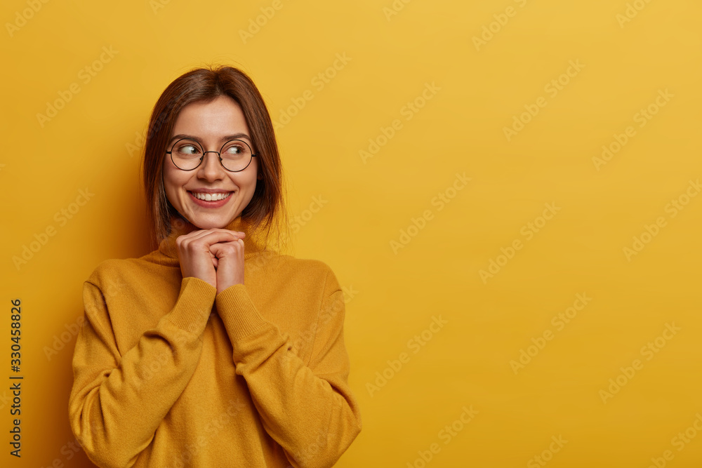 Cute tender woman looks at adorable kitten, keeps hands under chin, contemplates about something beautiful, wears spectacles and turlteneck, has lovely smile, dreams about something pleasant Cute tender woman looks at adorable kitten, keeps hands under chin, contemplates about something beautiful, wears spectacles and turlteneck, has lovely smile, dreams about something pleasant