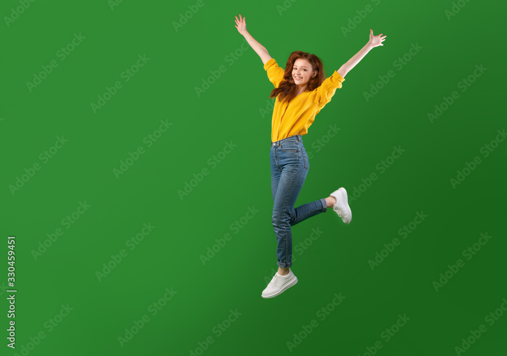 Joyful Girl Jumping With Raised Hands Over Green Studio Background