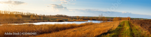 Panorama of steppe lake among fields and meadows during early spring. Countryside landscape.