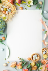 Happy Easter concept with easter eggs in nest and spring flowers. Easter background with copy space. Flat lay