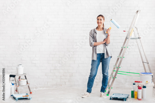 Happy young woman painting new home, copy soace © Prostock-studio