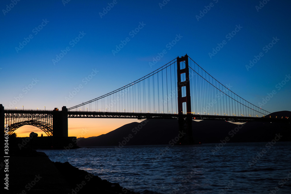 View onto the Golden Gate Bridge in San Francisco at sunset. It connects Peninsula and Marin Headlands. The San Francisco Bay is located on the eastern side of it.