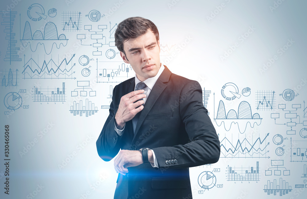 Young businessman with watch, graphs on wall Young businessman with watch, graphs on wall