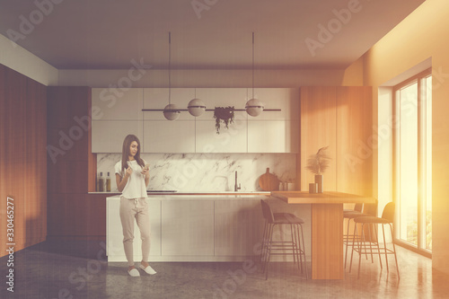Woman in white and wooden kitchen with bar