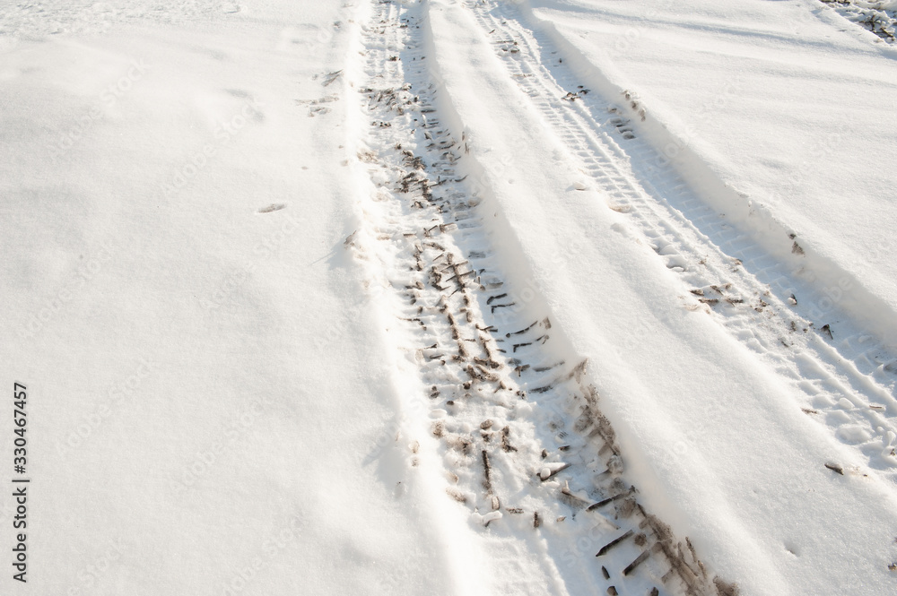 Tire tracks on a road covered by snow. Cold winter day.