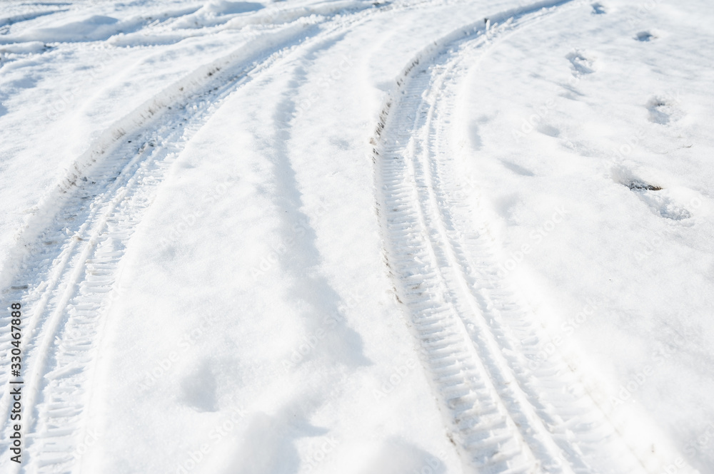 Tire tracks on a road covered by snow. Cold winter day.