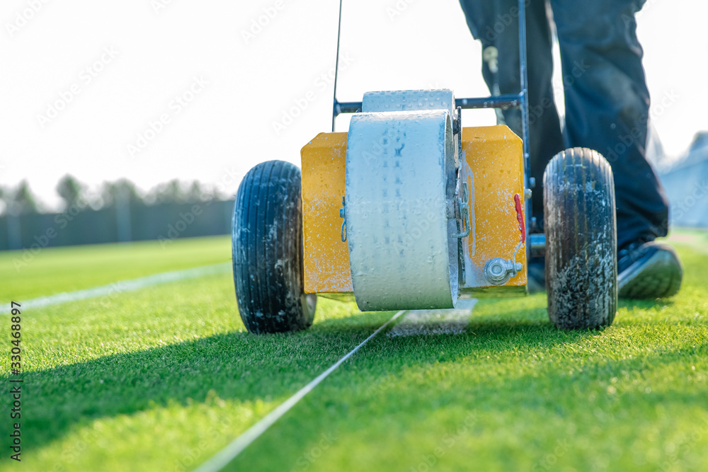 Fototapeta premium drawn white lines on the football field with white paint on the grass using a special machine before a game