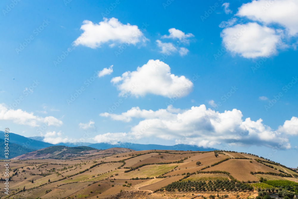 Naklejka premium Panoramic landscape of mountains and clouds and lovely field at foreground.