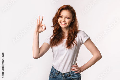 Girl Gesturing OK Smiling To Camera Posing Over White Background