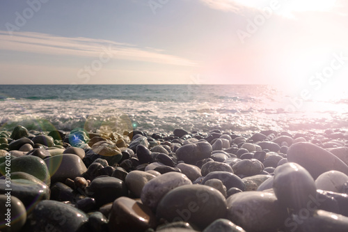 Sea shore with pebbles. wet sea pebbles on the beach and quiet sea surf © Aleksandr